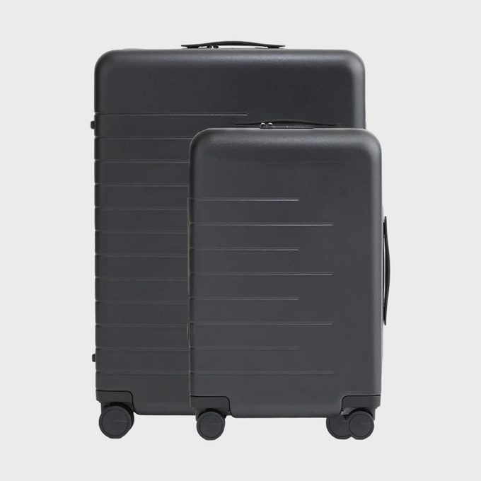 Two black suitcases stand upright on wheels, side by side, against a plain white background.