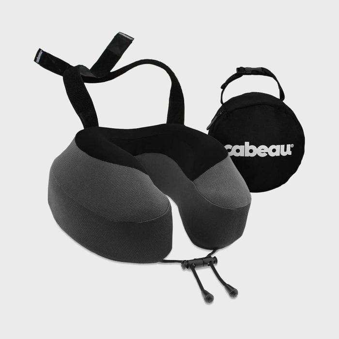 Neck pillow sits beside a small, round black travel bag labeled 