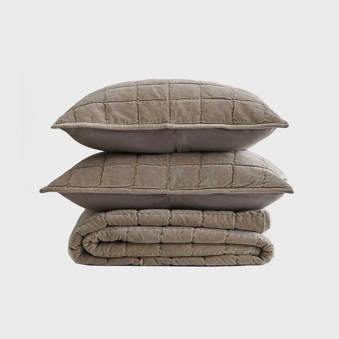 Two gray checkered pillows stack atop a folded quilt, set against a plain white background.
