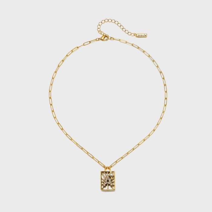 Gold chain necklace hangs, featuring a rectangular pendant with intricate starburst design, on a plain white background.