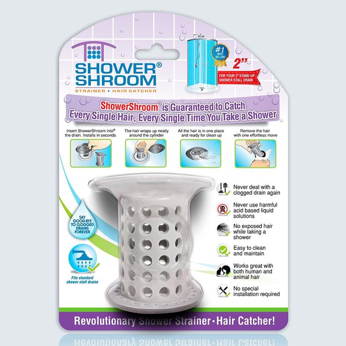 Strainer sits inside drain, catching hair in white perforated cylinder. Packaging shows installation steps, benefits, and highlights product as a shower essential.