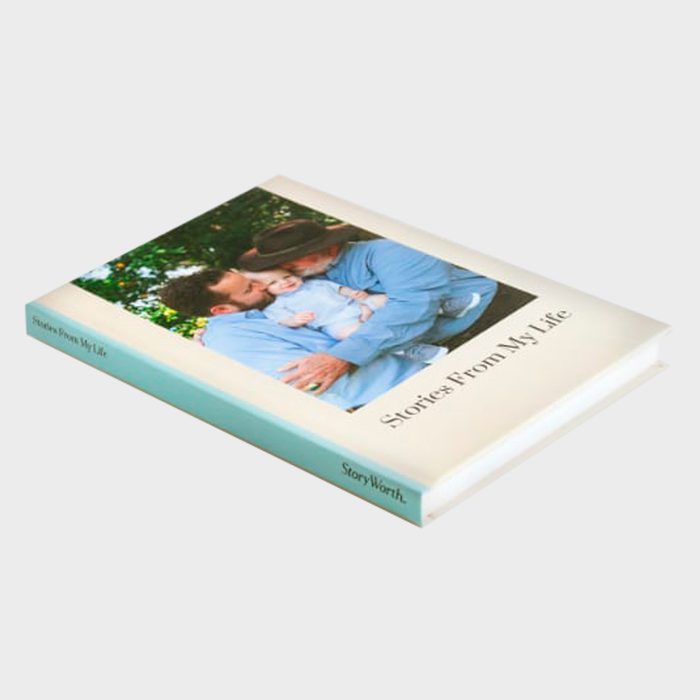 Book lies flat displaying a cover photo of two adults with child, surrounded by greenery. Text reads 