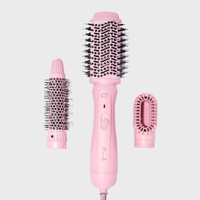 Pink hair styling tool with three interchangeable brush attachments on a plain background.