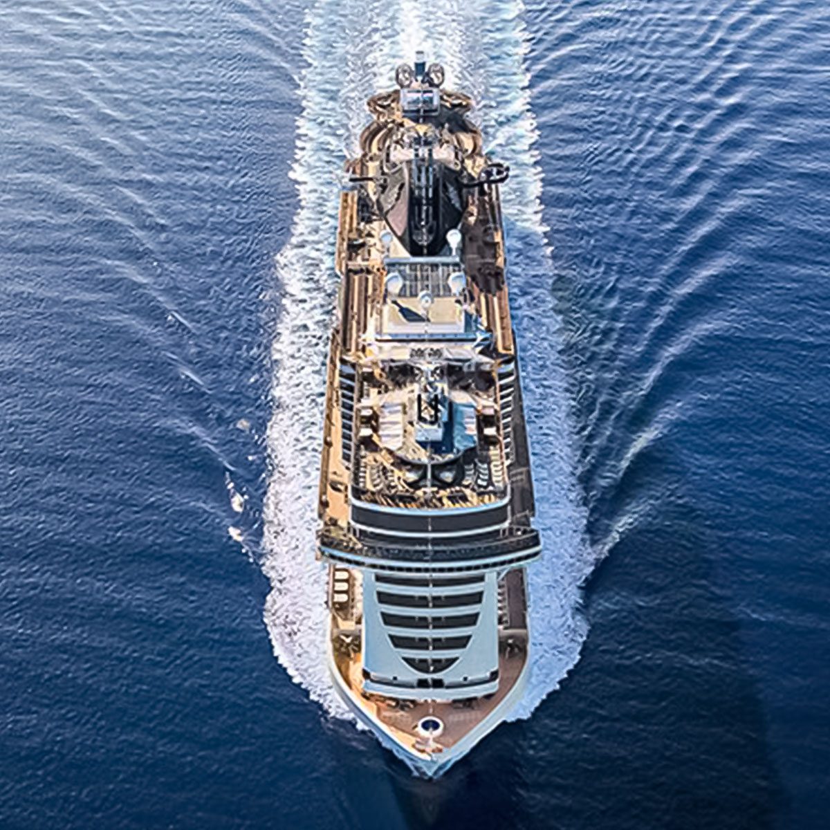 Cruise ship sails through calm, blue ocean, leaving a white wake behind.