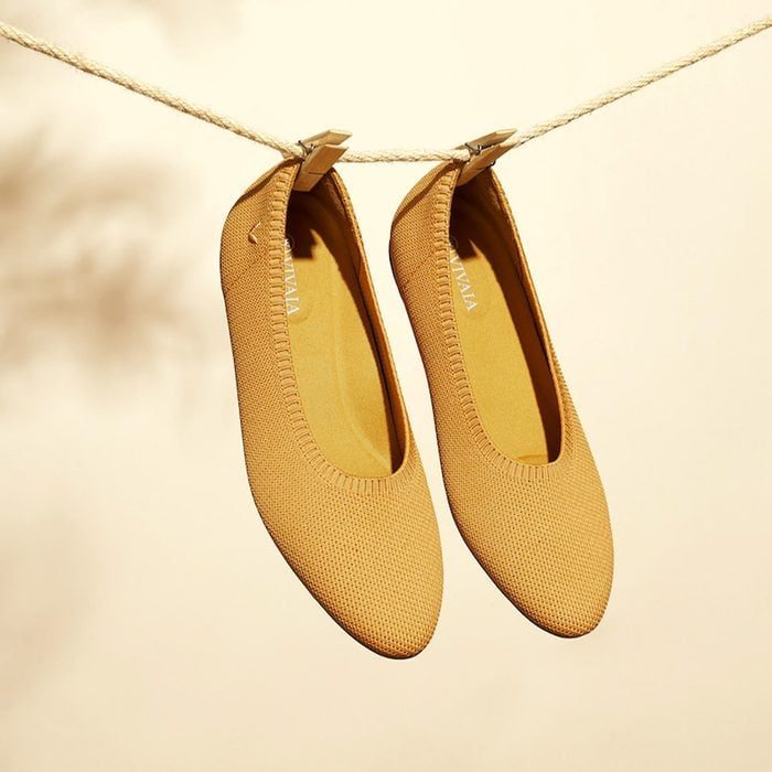 Two beige flats hang on a rope with clothespins against a light background.