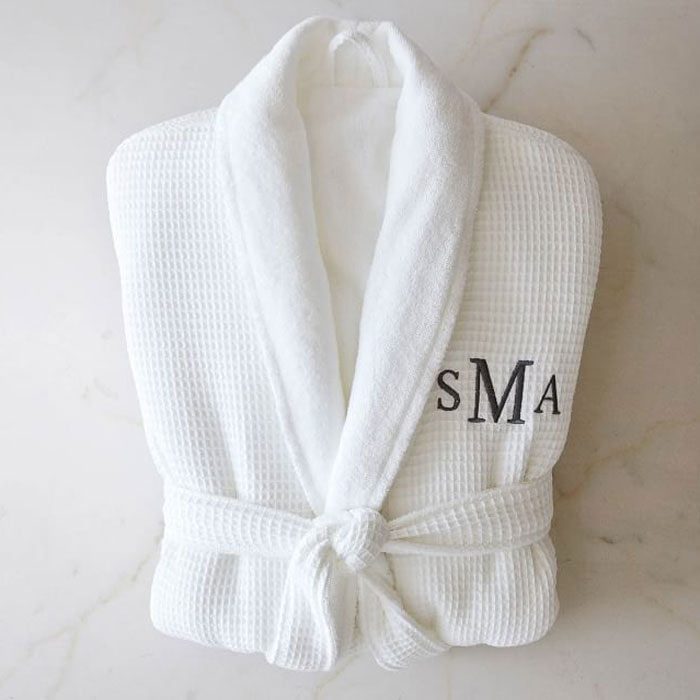 White bathrobe lies folded, monogrammed with 