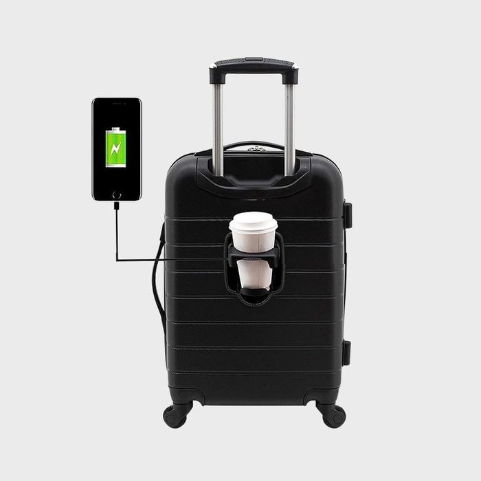 A black suitcase charges a smartphone via a cable, with a coffee cup held in a front pocket, set against a plain background.