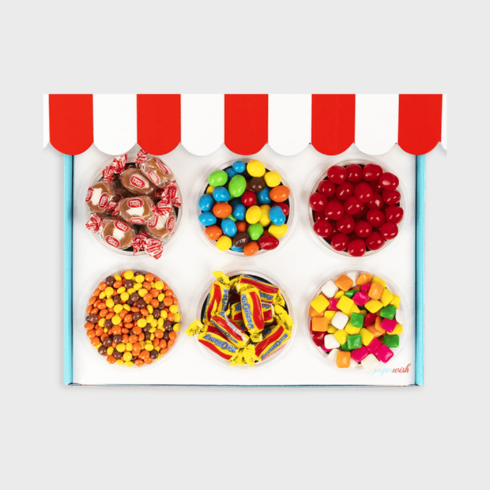 Assorted candies are arranged in six cups under a red and white striped awning on a white background.