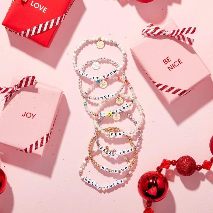 Bracelets display festive words on beads, surrounded by pink gift boxes with phrases like 