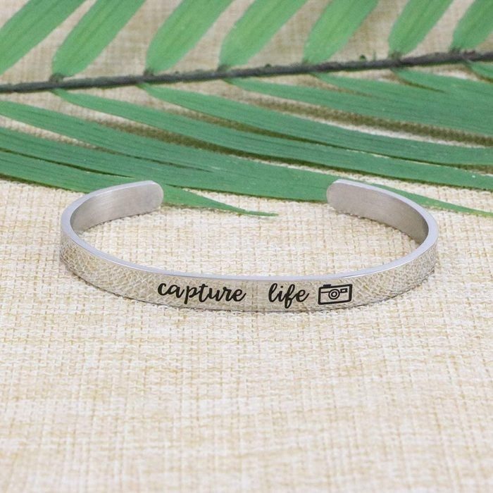 Bracelet rests on a woven surface, engraved with 