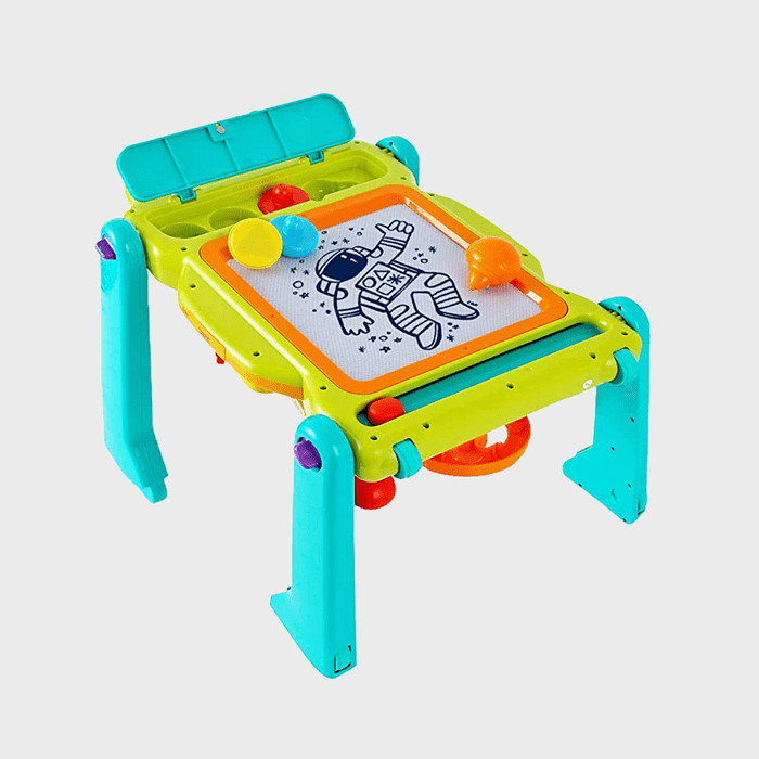 Plastic table with toy tools, features an astronaut drawing. Bright colors, surrounded by cylindrical objects on the tabletop in a playful setting.