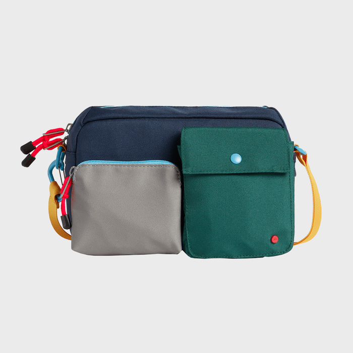 A color-blocked messenger bag, featuring multiple front pockets, rests against a plain background. It has a yellow strap and multicolored zippers.