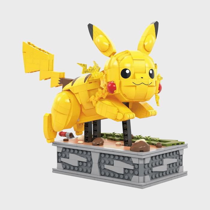 Lego Pikachu dashes energetically on ornate platform, surrounded by small rocks and plants, against a plain background.