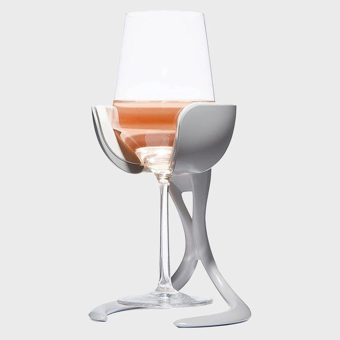 Wine glass held by a unique gray stand, containing rose wine, set against a plain light-gray background.