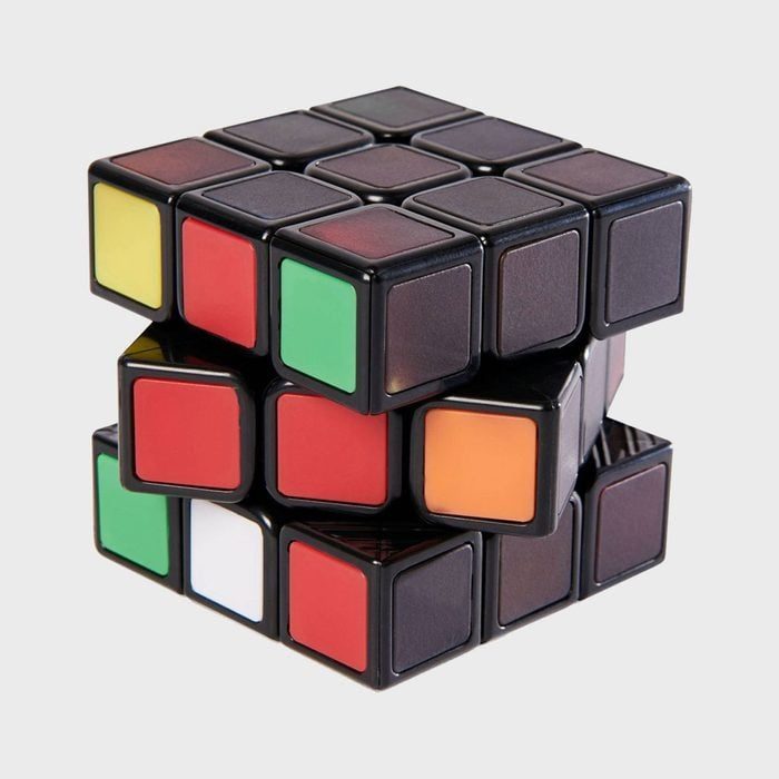 Rubik's Cube partially twisted with colorful squares; colors include red, green, orange, yellow, white. Set against a plain gray background.
