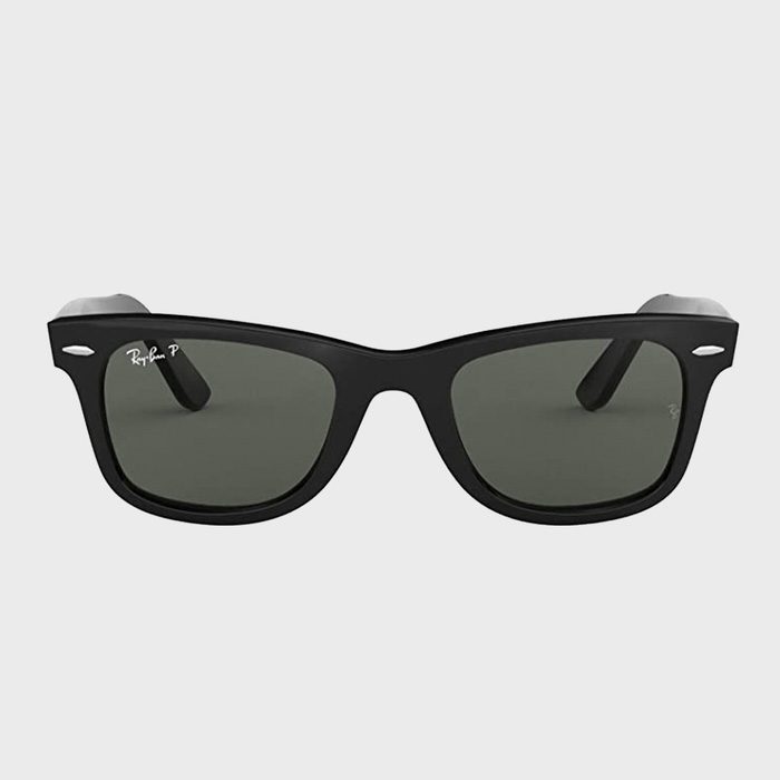 Sunglasses rest on a flat gray background; black frame with dark lenses. 