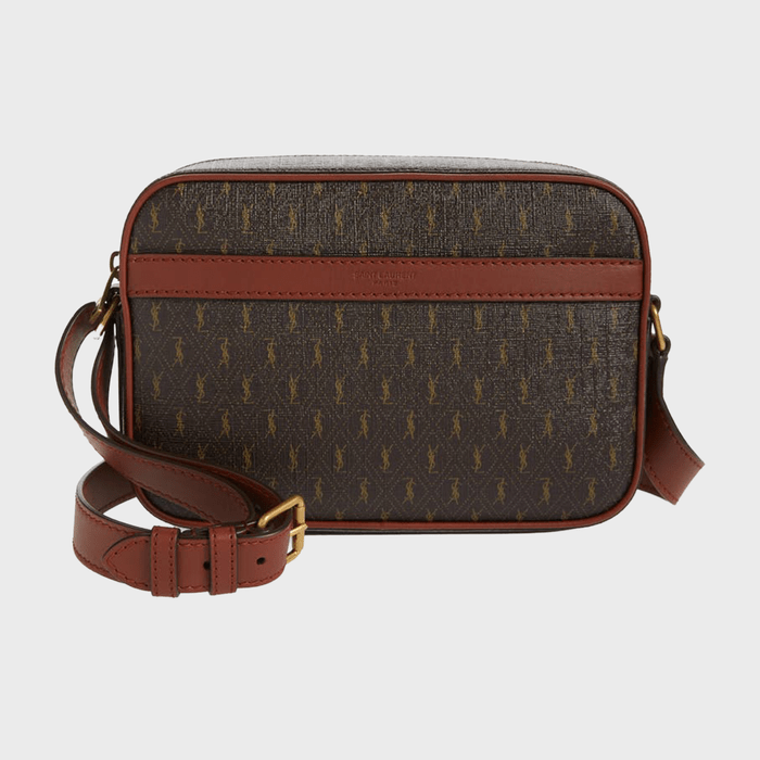 A brown monogram crossbody bag rests upright with an adjustable leather strap, set against a plain background.