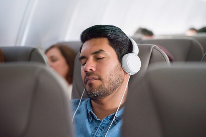 man with over ear headphones sleeping on flight