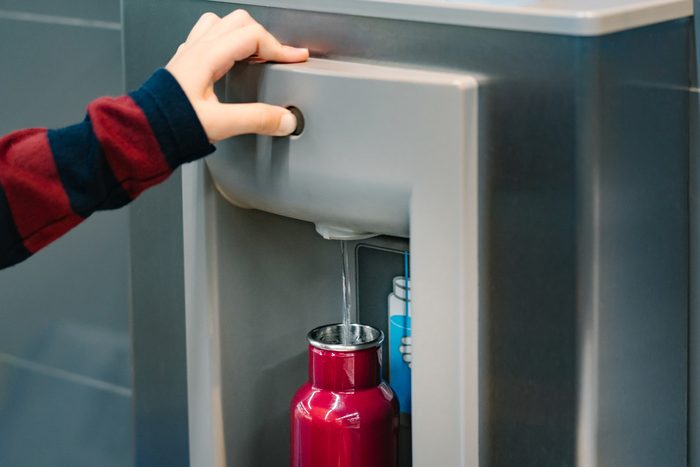 refilling reusable water bottle from water filling station at airport