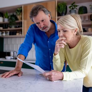 Concerned older couple reading a letter at a kitchen counter
