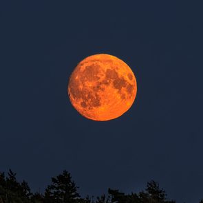 The rising moon looks like a red ball hanging in the sky