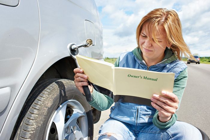 Woman reading owner's manual of car