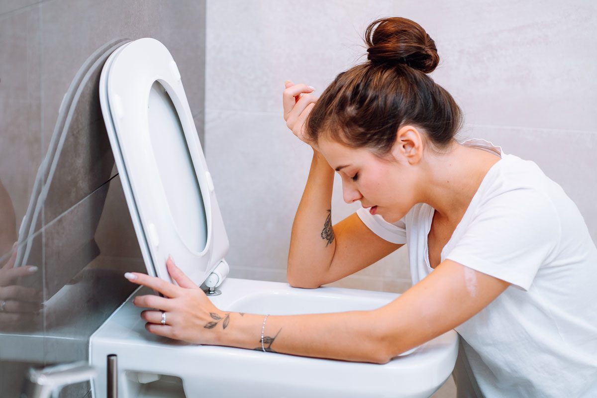 Young Woman Vomiting In Toilet