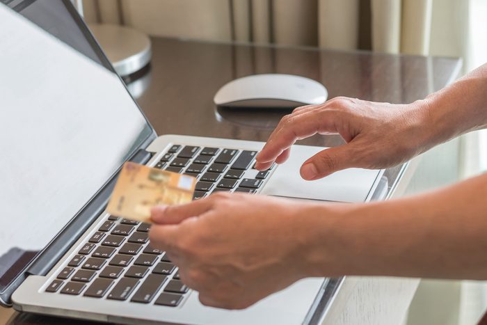 person using laptop while holding credit card