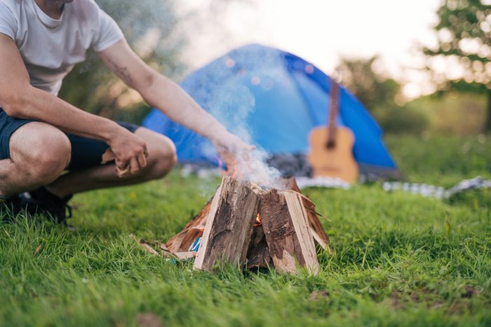man making fire while camping in nature