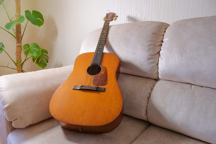 Old acoustic guitar lying on the sofa in the living room.