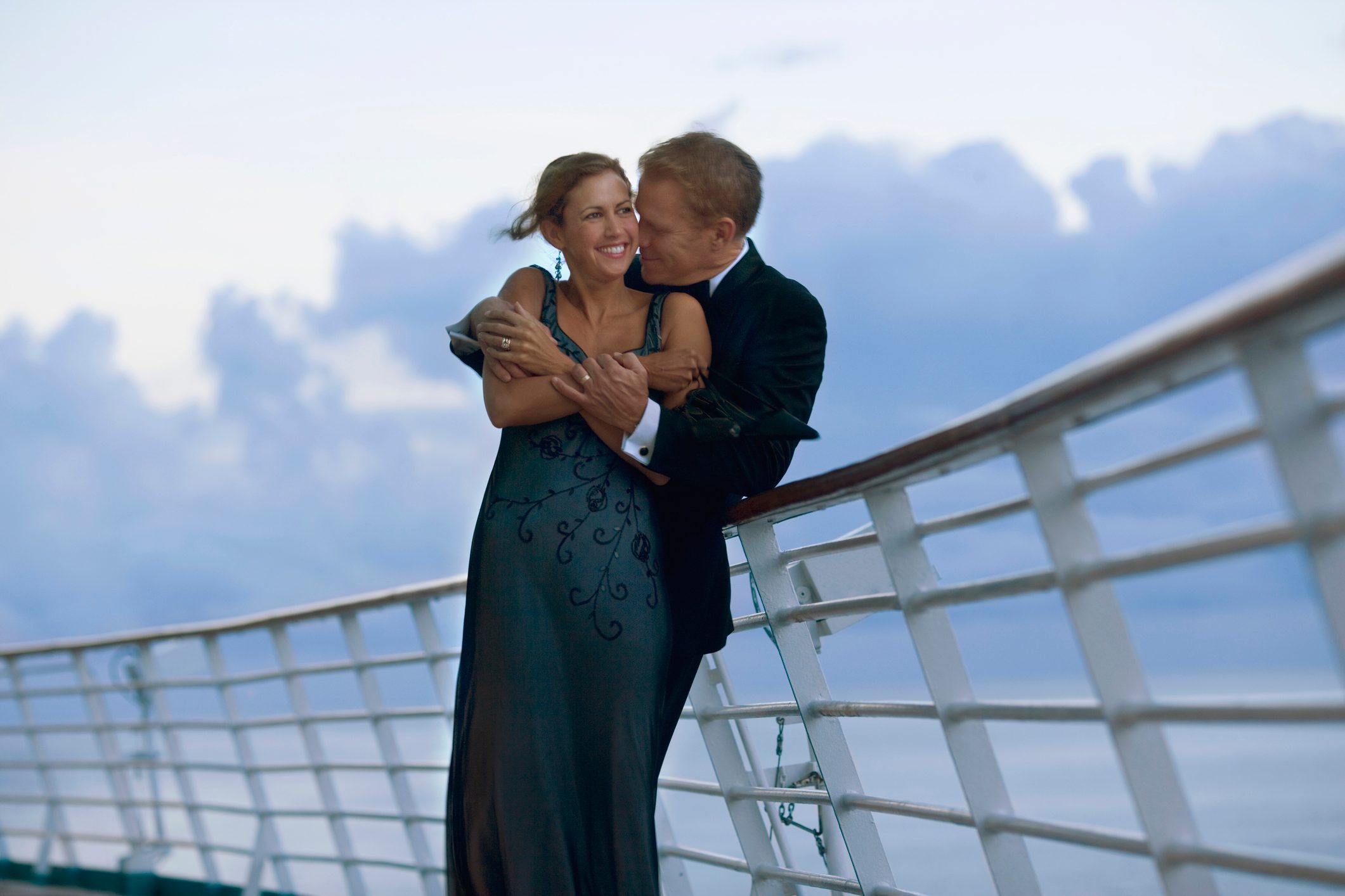 Couple on cruise ship deck, smiling in formal wear
