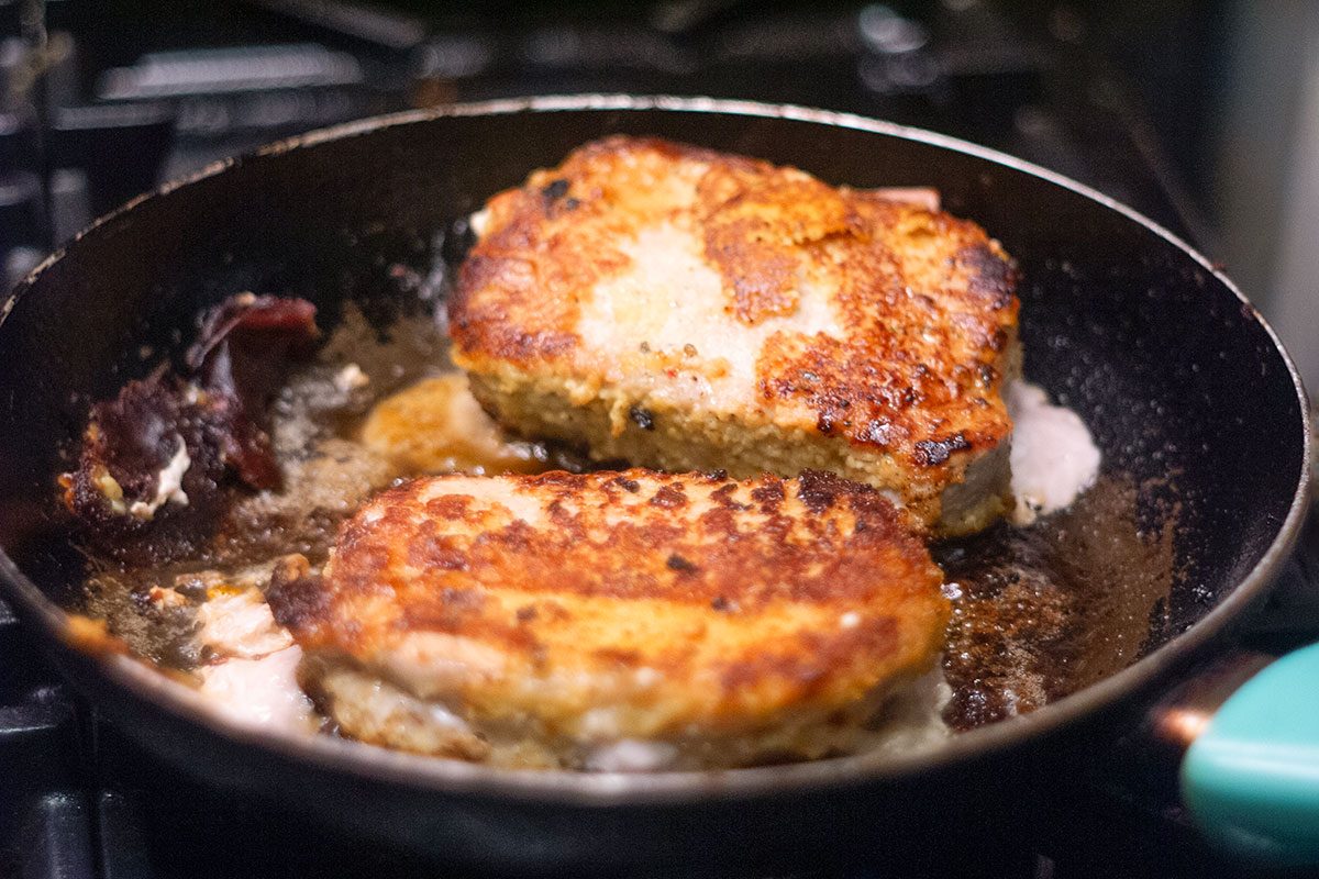 Pan on stove with chicken cooking.