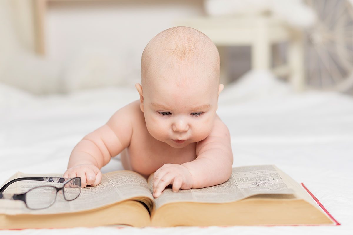 aby reading a book or looking at it in the nursery