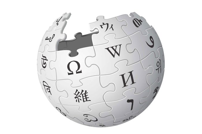 A globe comprised of jigsaw puzzle pieces displays various letters. It's partially assembled, set against a plain background.