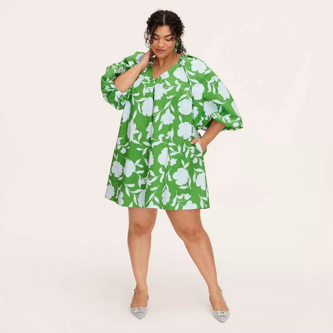 Woman in a green printed dress on a tan background