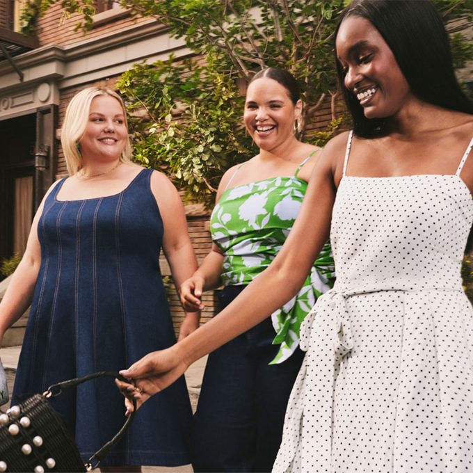 Three women holding Kate Spade purses on a city street