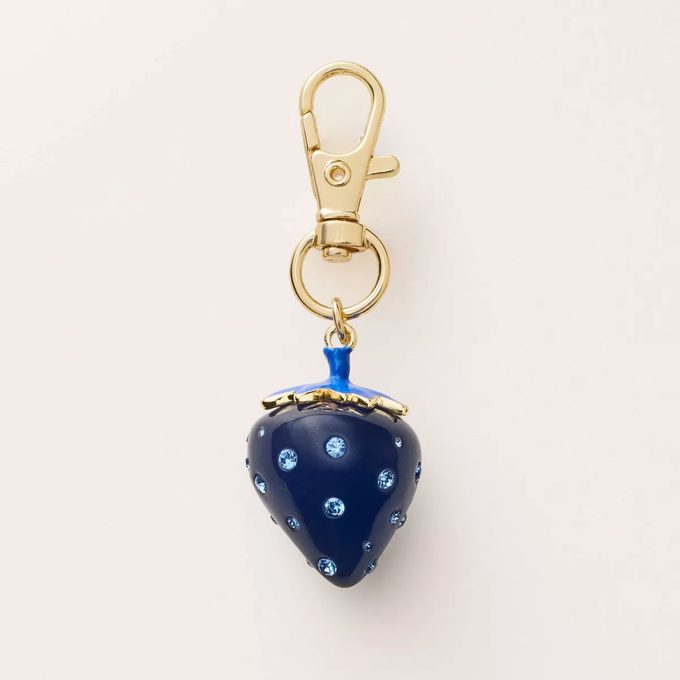 Blue strawberry keychain on a tan background