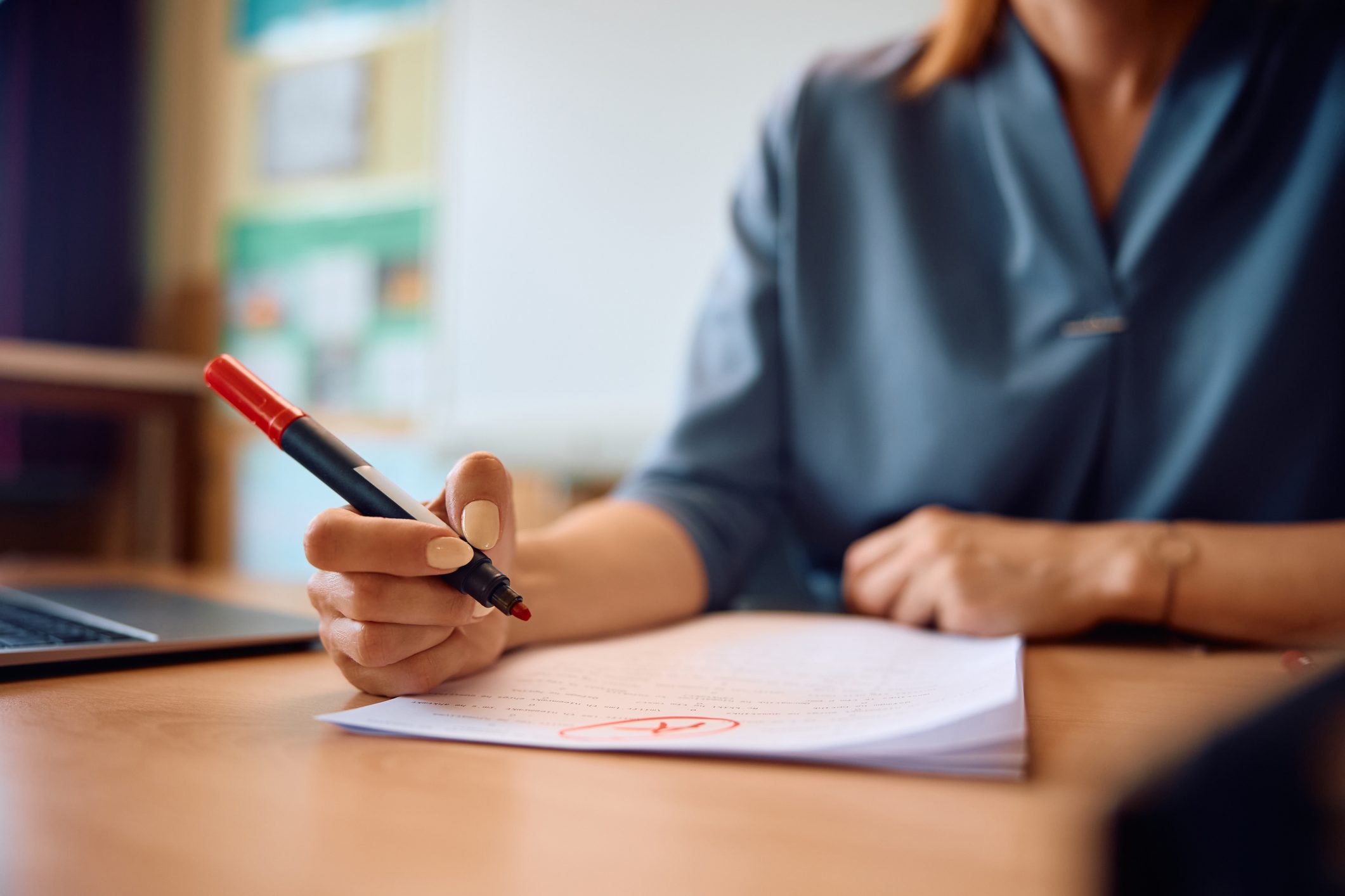 Close up of teacher grading tests of her students in the classroom.